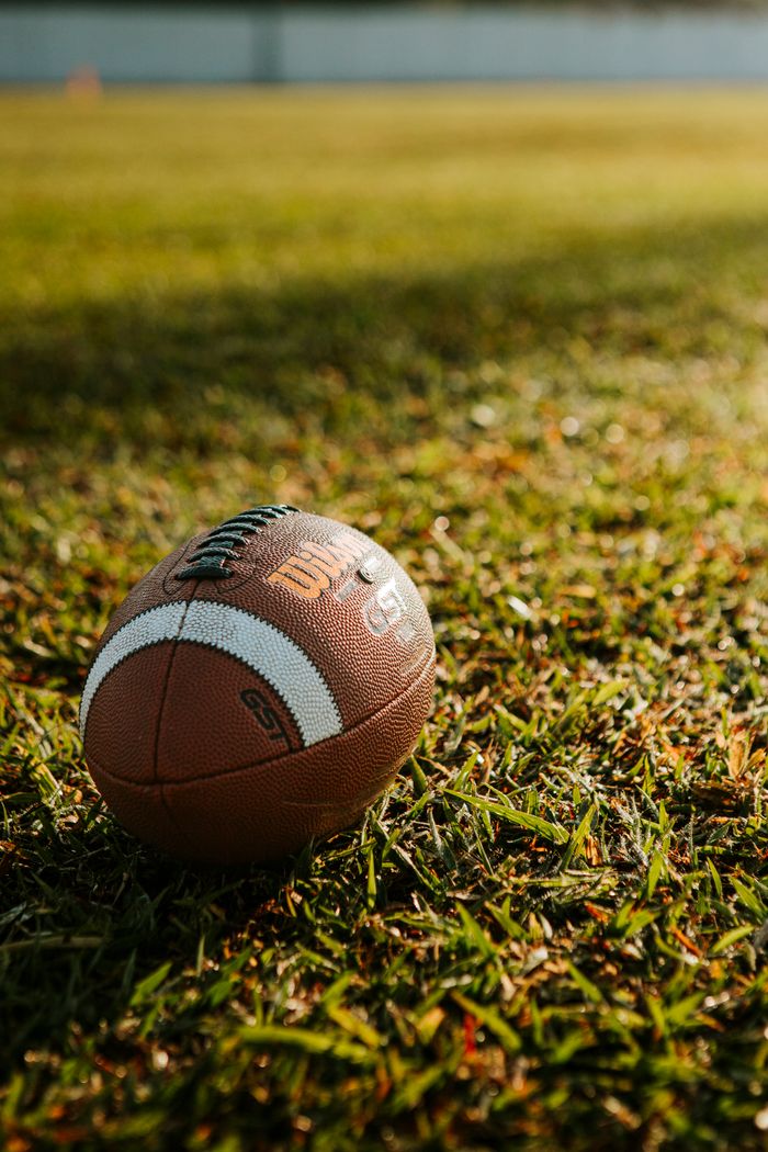 Close-up shot of a football resting on a sunlit grass field, ideal for sports themes.
